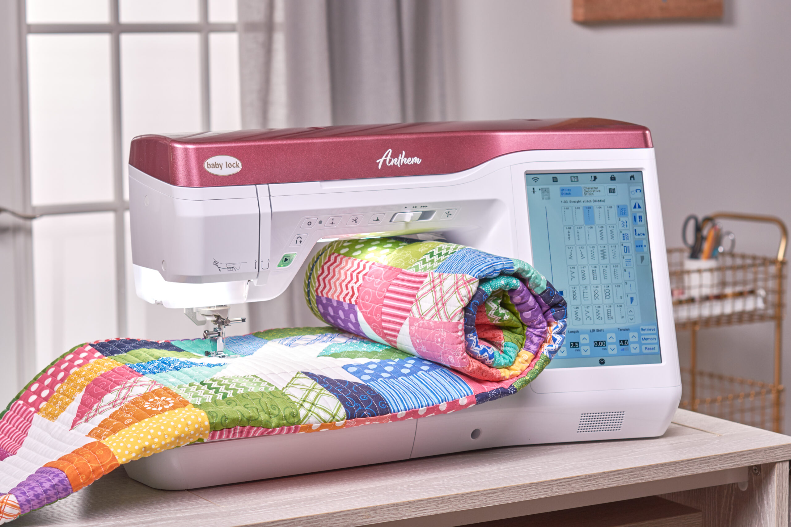 Baby Lock Anthem sewing machine with a colorful folded patchwork quilt extending through its sewing workspace.
